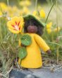 Close up of the Ambrosius eco-friendly Nasturtium doll on a rock in front of some yellow flowers