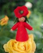 Close up of the handmade felt Ambrosius poppy crown fairy doll on a yellow flower in front of a green background