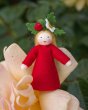 Close up of an Ambrosius strawberry crown fairy doll on a pink flower in front of a green background