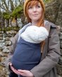 Close up of woman leaning against a stone wall wearing the close caboo organic baby carrier in the blueberry colour
