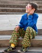 Boy sat on a step wearing the DUNS eco-friendly organic cotton baggy pants in the foliage green radish colour
