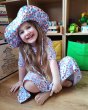 Young girl sat on the floor wearing the DUNS Sweden organic cotton skater dress and sun hat in the purple strawberries colour