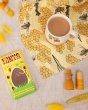 Close up of the DUNS Sweden eco-friendly bee yellow tea towel next to a bar of lemon meringue tony's and a mug of coffee