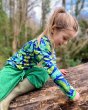 Child sat on a large log wearing the DUNS Sweden eco-friendly blue frog organic cotton long sleeve top
