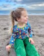 Child sat on a beach wearing the DUNS Sweden organic cotton blue citrus long sleeve top