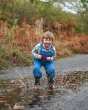 Boy jumping in a puddle wearing the Babipur exclusive Frugi Pluto cord dungarees in the loch blue colour