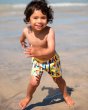 Close up of young boy running on the sand wearing the Frugi childrens surfs up board shorts