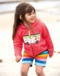 Young girl stood on a beach wearing the Frugi organic cotton harley campervan hoodie