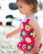 Young girl walking on sand wearing the Frugi flower power newlyn nappy swimsuit