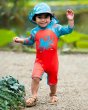 Young boy walking on some sand wearing the Frugi childrens little sun safe suit in the octopus print