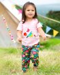 Young girl walking through a grass field wearing the Frugi floral organic cotton snuggle crawlers 