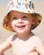 Close up of young child wearing the yellow Frugi surfs up sun hat on some sand