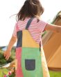 Girl facing backwards wearing the Frugi eco-friendly rainbow hotch potch block dress