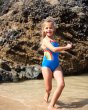 Young girl walking in the sea wearing the Frugi eco-friendly rainbow stripe thea swimsuit