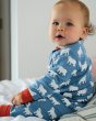 Toddler sat on a bed wearing the soft cotton Frugi zennor zip up romper suit in the polar bear print