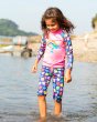 Young child stood in the sea wearing the Frugi seashells sun safe set