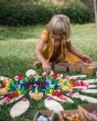Close up of a girl playing with the Grapat handmade mandala toy pieces on the large petal blocks, laid out on some grass