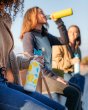 Close up of woman holding the Klean Kanteen 27oz lemon sports bottle next to a woman drinking from a klean kanteen metal bottle