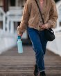 Close up of lady walking and carrying the Klean Kanteen 27oz narrow metal water bottle on a wooden path