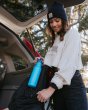 Girl putting the Klean kanteen 18oz reusable metal sports bottle in the side pocket of a backpack