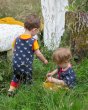 2 boys playing in some long grass wearing the Little Green Radicals organic cotton whale song everyday dungarees