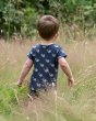 Boy walking through a grass field wearing the eco-friendly little green radicals whale song shortie