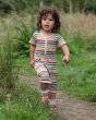 Child walking around in a grass field wearing the Little Green Radicals rainbow stripe shortie