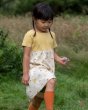 Close up of girl walking in a grass field wearing the Little Green Radicals organic cotton sunshine and rainbows easy peasy dress