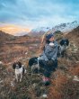 Woman sat next to some dogs on top of a mountain wearing the Mamalila babywearing outdoor adventure jacket