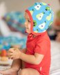 Young child sat wearing a red top and the Maxomorra pear print helmet hat