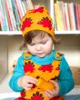 Close up of a child playing with a toy wearing the Maxomorra eco-friendly dino dungarees and dino beanie hat