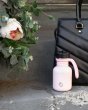 One Green Bottle 350ml plastic free water bottle on a step in front of a black hand bag and next to a white flower 