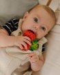 Close up of a toddler chewing on the oli and carol natural rubber raspberry teething toy 