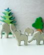 2 Ostheimer wooden elephant toy figures stood on a white table in front of some wooden Bumbu tree toys