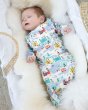 Baby laying on a white fluffy blanket wearing the Piccalilly organic cotton baby nightgown in the little london print 