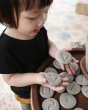 Close up of a girl holding the plan toys sensory tactile stone blocks over a round wooden table