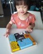 Girl looking at the Plan Toys eco-friendly wooden animal figures jigsaw puzzle game on a white table