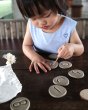 Girl tracing around the carvings in the Plan Toys wooden tactile stones on a dark brown table
