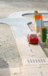 Plan Toys Standard Road System pictured set up on concrete connected to the rubber road set with a red vehicle on the road