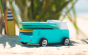 Close up of a candylab wooden beach van toy vehicle on some sand with mini surfboard toys on the back