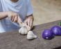 Child cutting up play food garlic with a wooden toy knife.