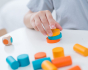 Close up of child stacking up the coins in the PlanToys mini stacking game.