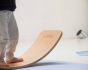 Close up of child standing on a Wobbel balance board in a white room