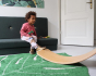 Child resting his foot on a Wobbel Bamboo balance board on a green leaf carpet