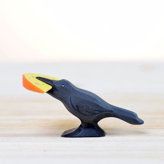 Bumbu handmade plastic free wooden raven and cheese set on a white wooden background with the raven holding the cheese in its mouth