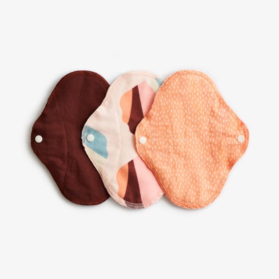 Imse Classic Cloth Pads - Small 3 pack - Orange Sprinkle period pants in plain rust orange, orange, beige, rust, blue and pink and orange with white dots all with white popper snaps on a white background