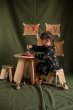 Girl sat painting at a Babai flat packed wooden table on top of a green sheet