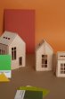 Small medium and large babai dollhouses on a brown table in front of an orange wall