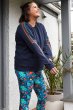 Woman stood on under a porch wearing the Frugi organic cotton juno lightning bolt jumper in dark blue