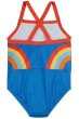 back of blue swimsuit for children with a retro rainbow design stretching around the sides, a contrasting red trim and cross-over straps from frugi